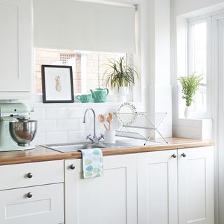 kitchen with white walls wooden worktop and white kitchen cabinet