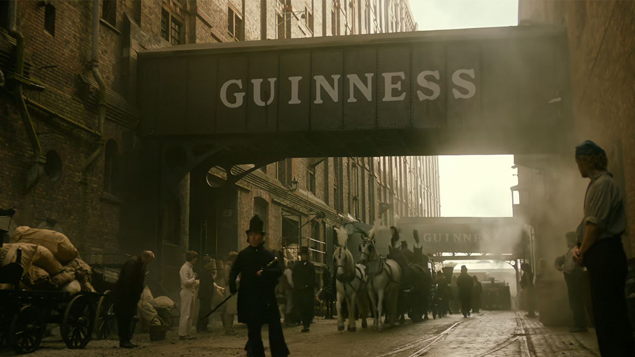 A funeral procession for Benjamin Guinness walking under a sign for Guinness in House of Guinness