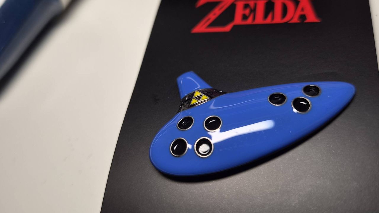 Close up of the Ocarina of Time pin on its black backing packaging.
