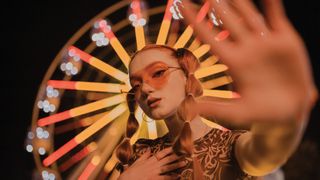 Woman standing in front of a ferris wheel at night