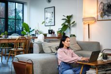 woman sitting on living room floor home using laptop, working from home