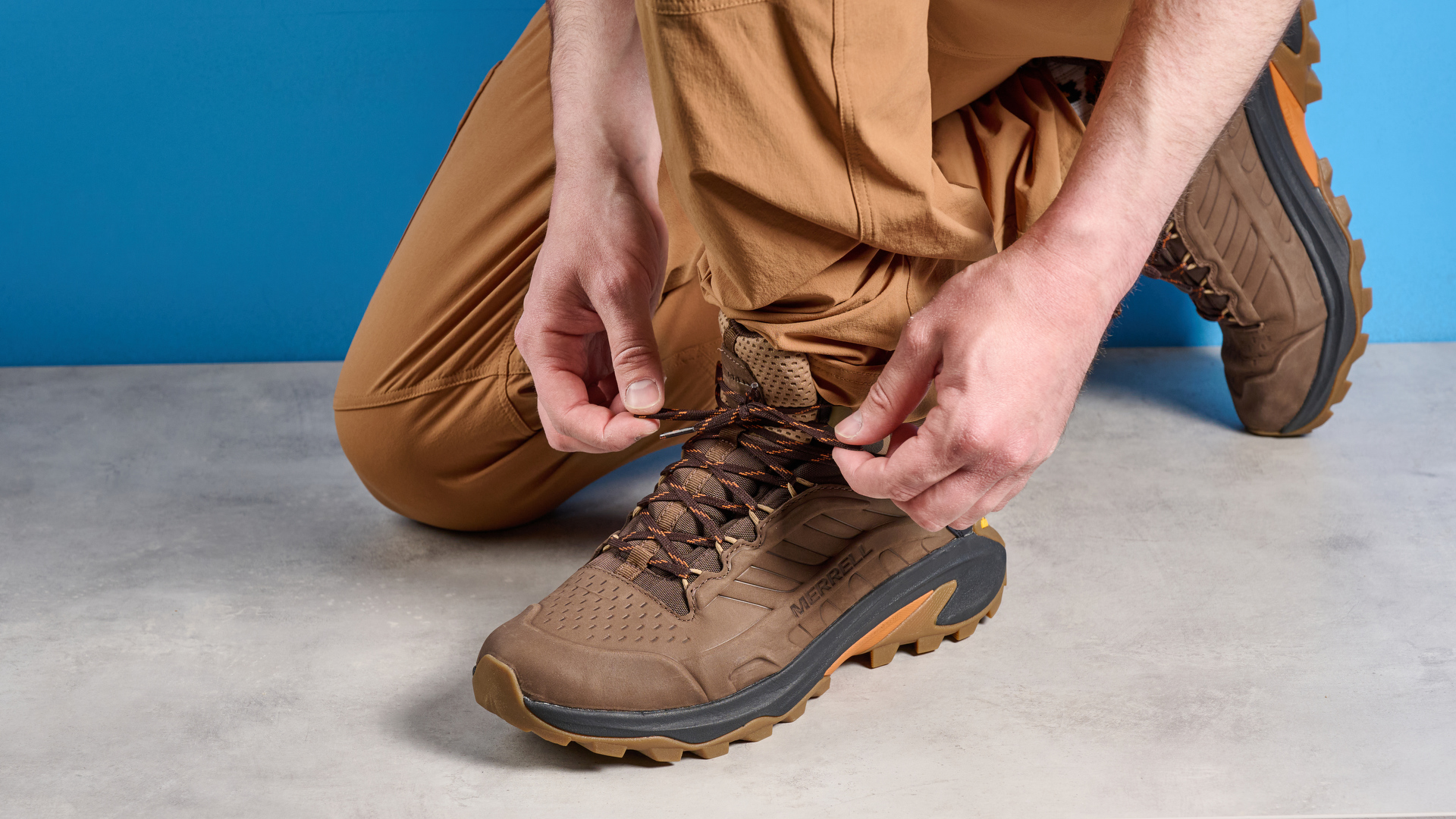 A photo of the Merrell Moab Speed 2 boots against a blue background