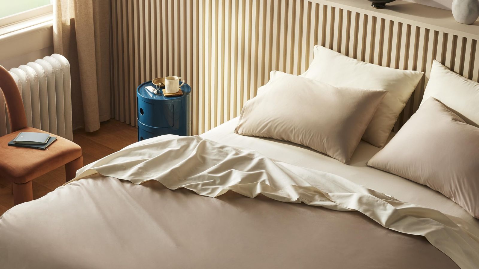 Brooklinen sateen sheets on a bed against a beige wall. 