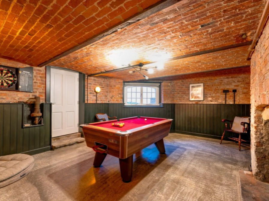 A games room in a cellar with a pool table and darts board