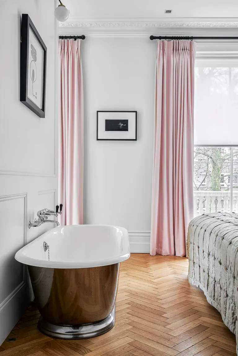 Bedroom with silver freestanding bath and long pink curtains