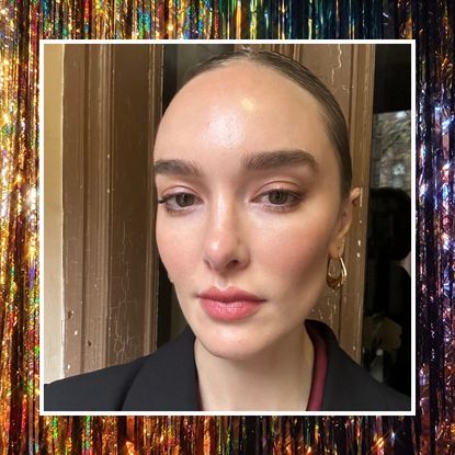 a woman with glitter eyeliner and a black jacket with gold hoop earrings on a sparkle background