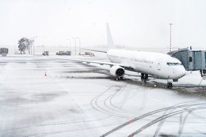Airplane docked at airport during a snowstorm