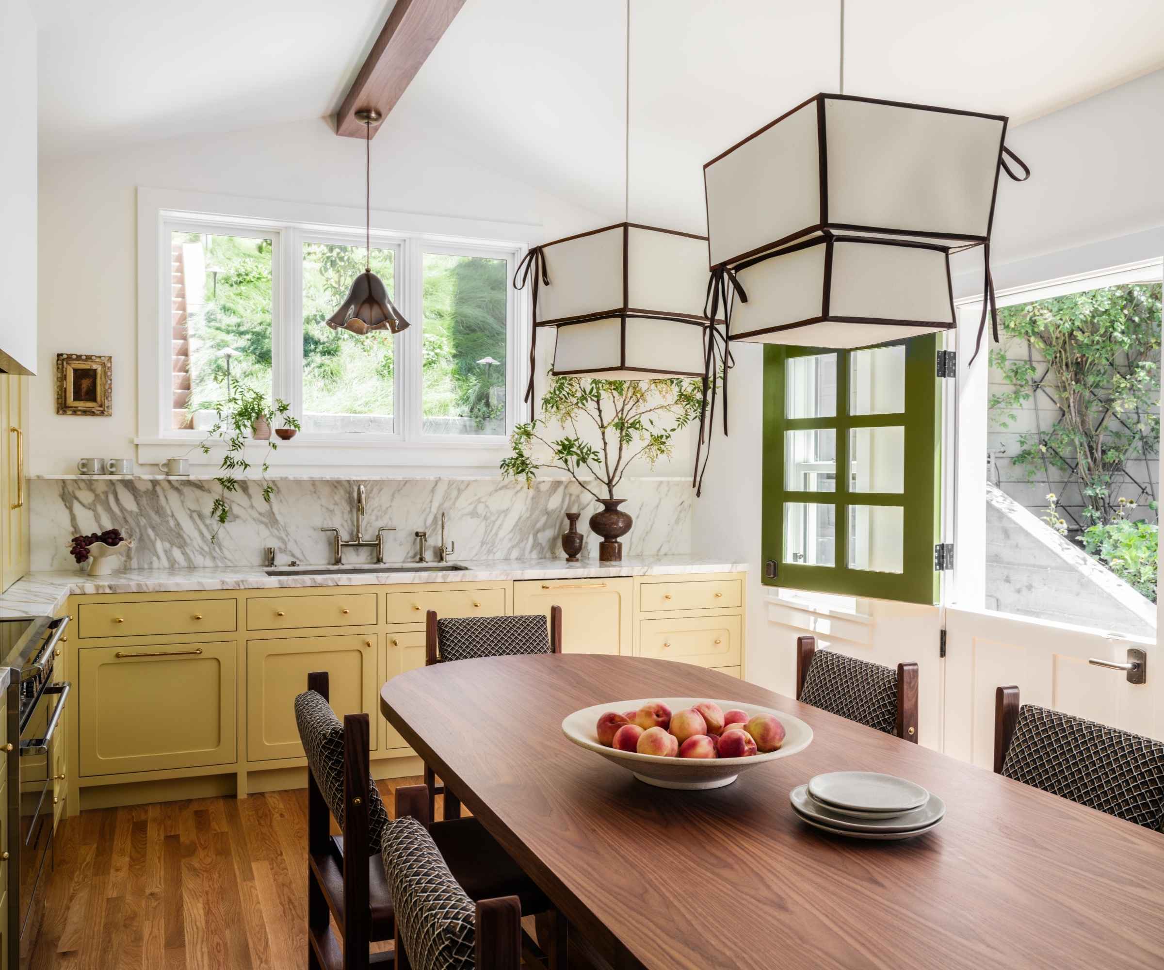 A yellow kitchen with a large wooden table and marble countertops