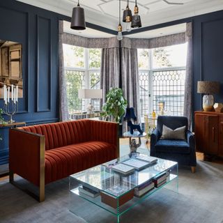 Blue living room with rust red sofa and two corner bay windows