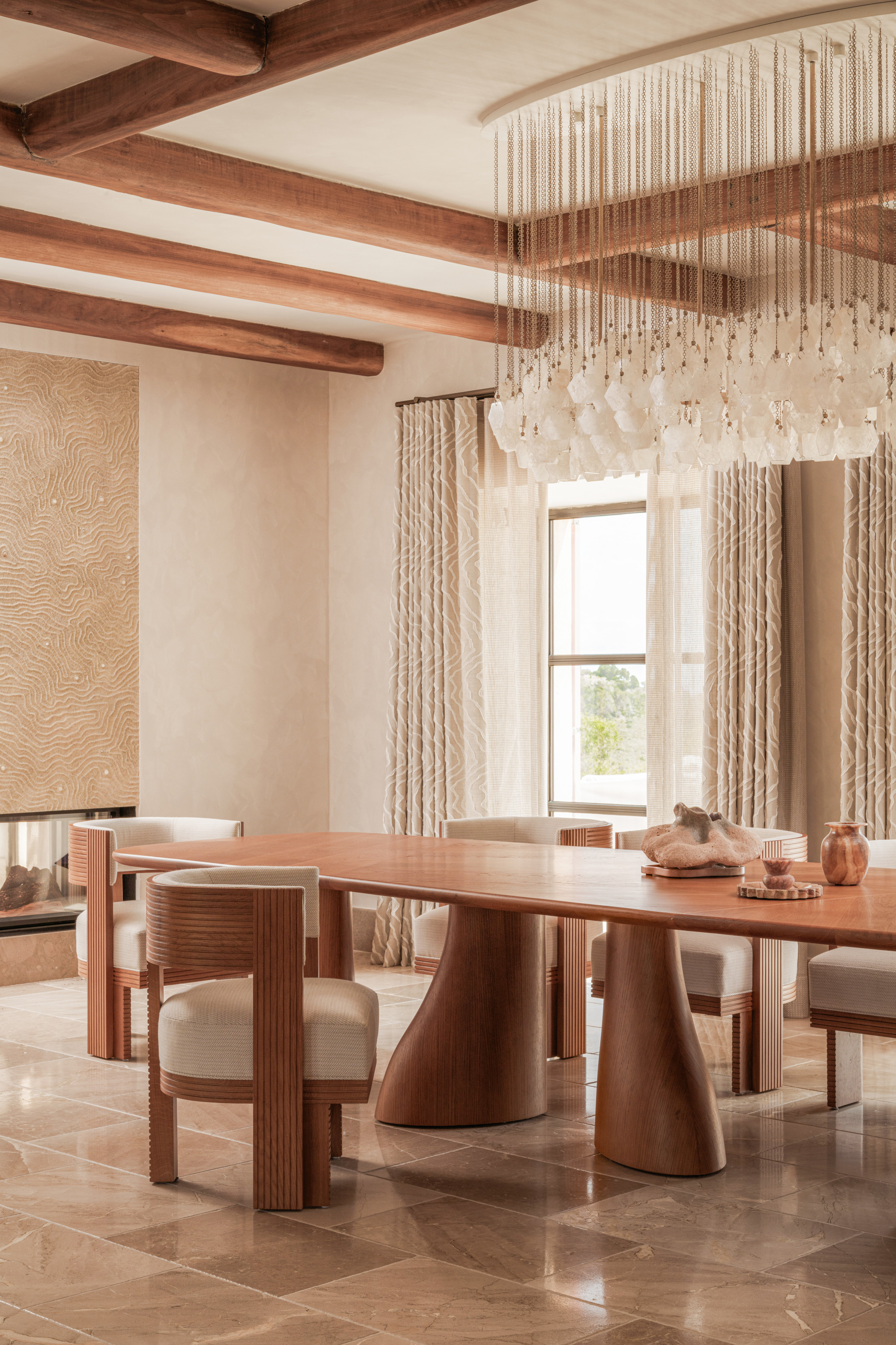 Cream dining room with wood oval table, curved wood armchairs and chandelier