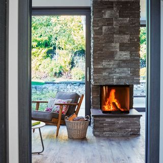 living area with grey stone wall and fire place and brown chair