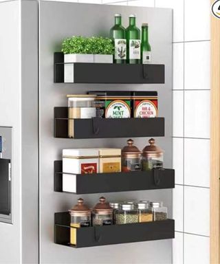 Four black magnetic spice racks on the side of a gray metal fridge