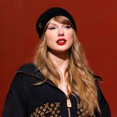 Taylor Swift wearing a red lip color and beanie hat with her hair down.
