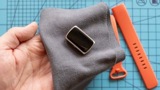 Polishing a Fitbit Charge 6 with a microfiber.