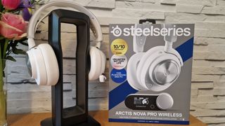 The SteelSeries Arctis Nova Pro Wireless white edition on a headset stand with a white brick background