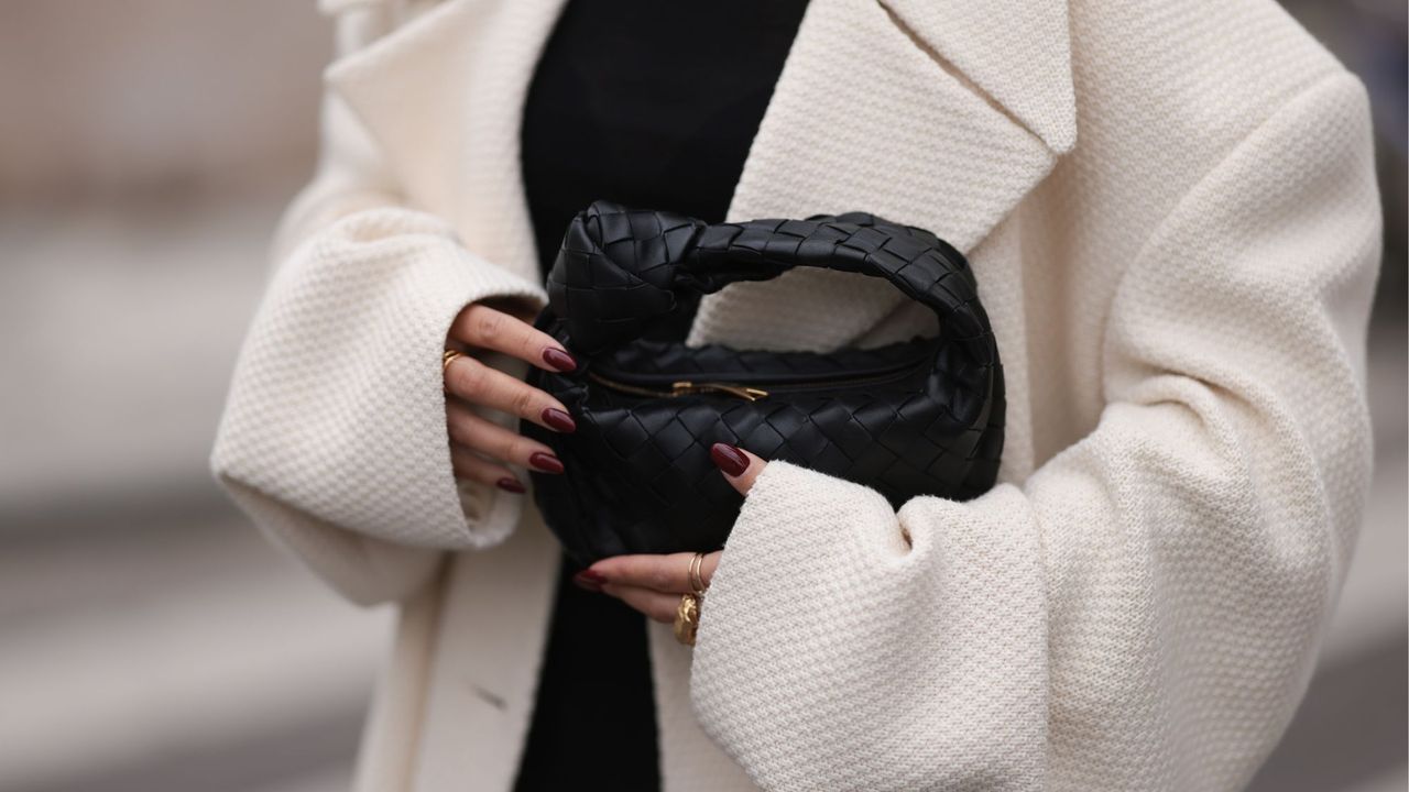 Woman holding black bag wearing burgundy nails