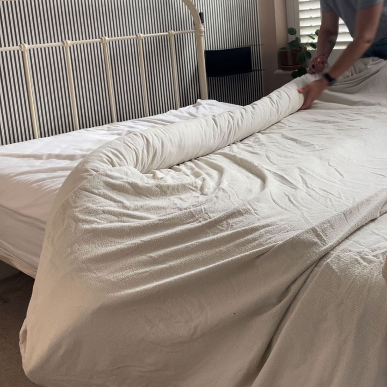 A woman putting a duvet cover onto a duvet using the 'burrito' method
