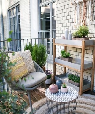 Small garden plants in modern containers on colorful balcony with outdoor furniture