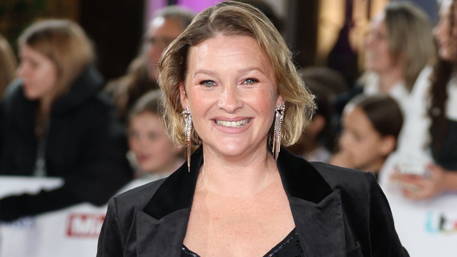 Joanna Page on the red carpet wearing a black blazer with glowing skin