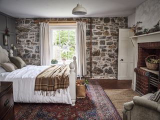 cottage bedroom with thick stone walls and sash window
