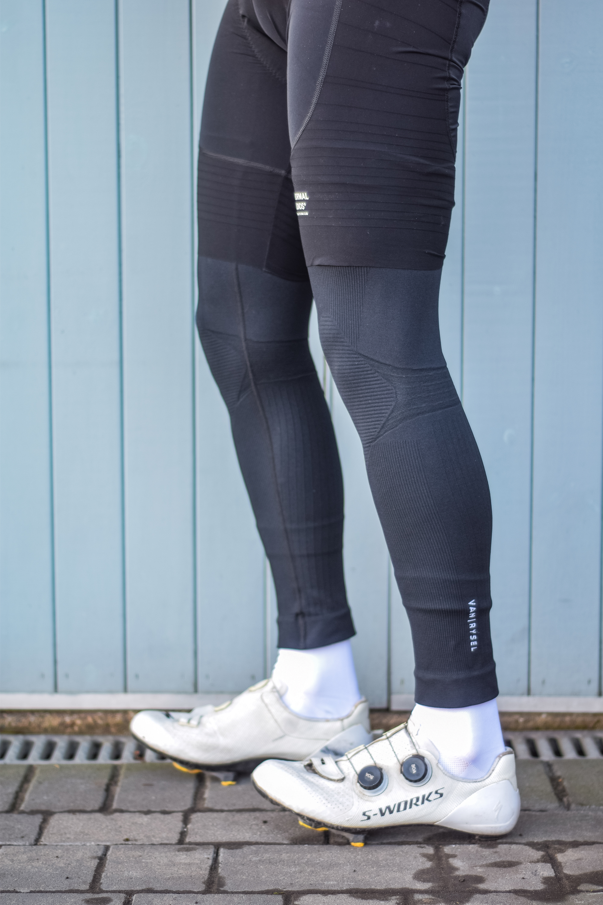 A man wearing cycling shorts and leg warmers in front of a blue door 