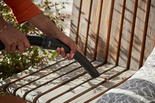 A woman vacuums leaves up from her deck