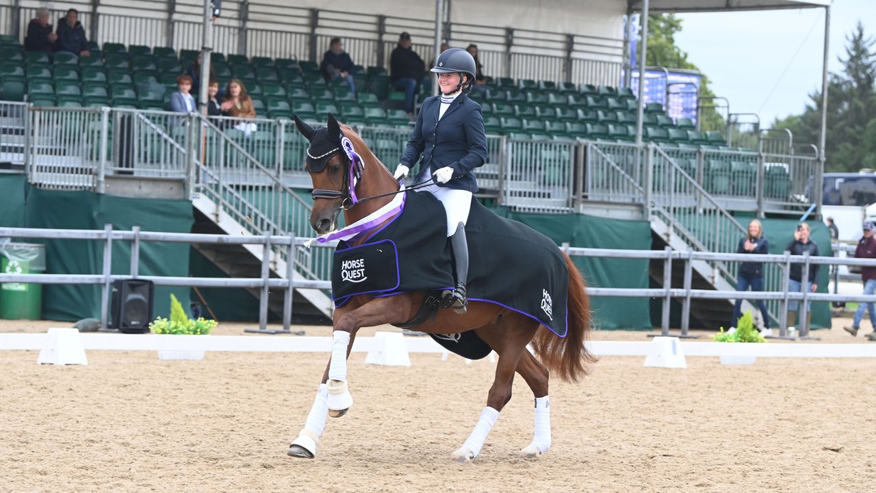 Amber Flynn rides XXX who is wearing a black and purple winners rug over XXX saddle and a rosette attached to her bridle