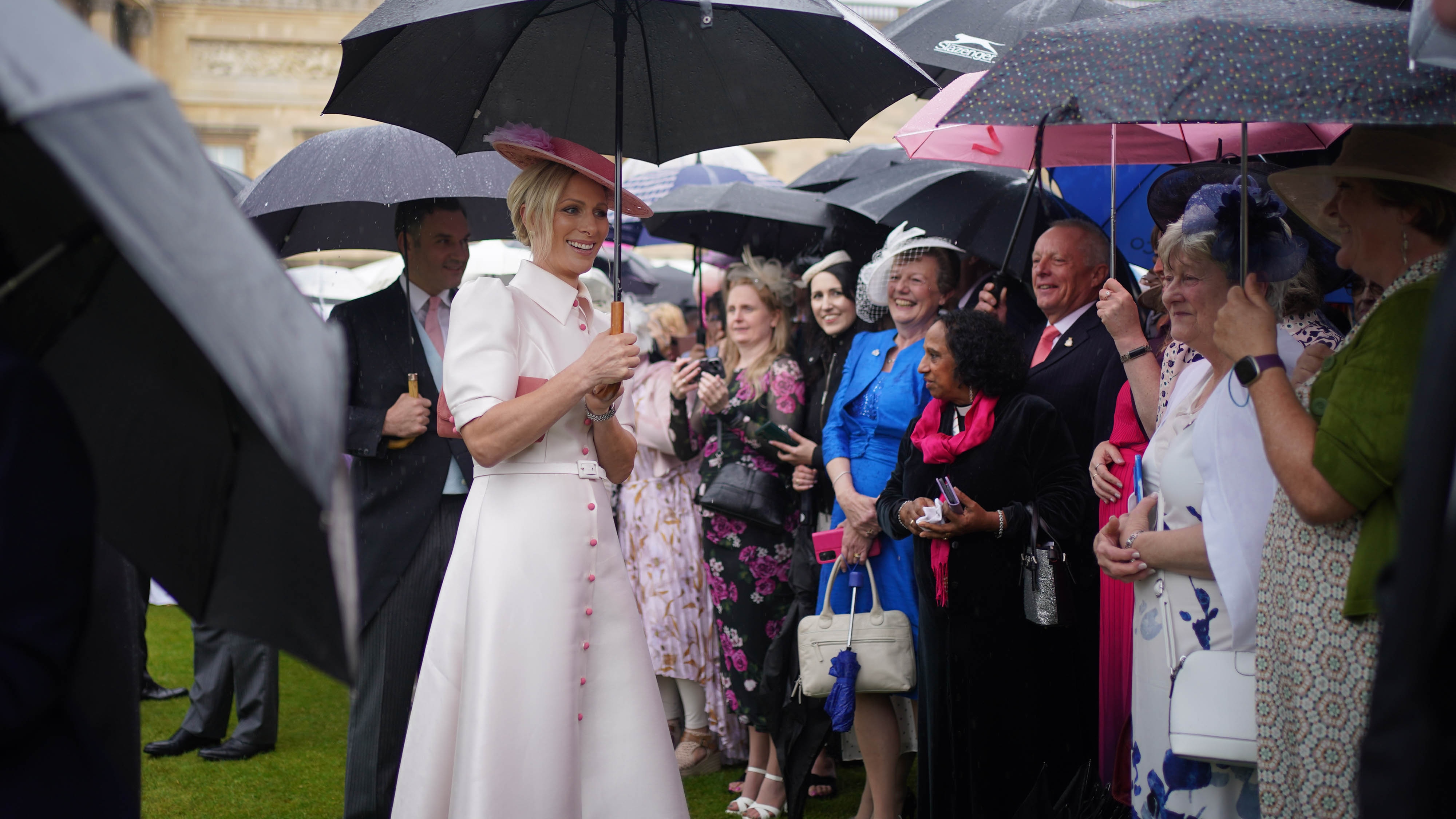 Zara Tindall drží deštník, když se účastní zahradní párty v Buckingham Palace 21. května 2024