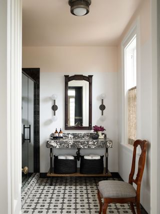 bathroom with dark wood mirror marble vanity unit and tiled floor