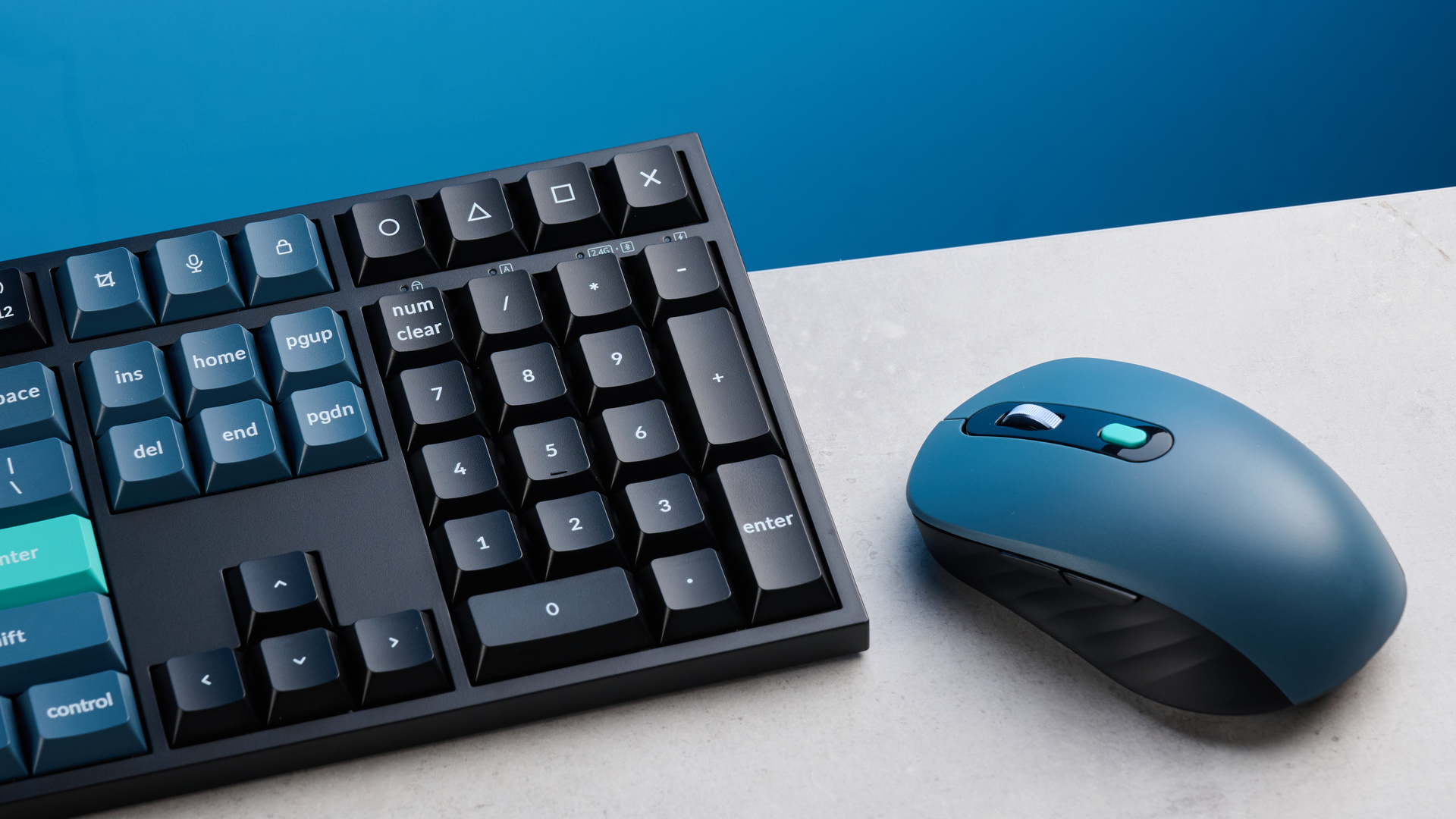 Keychron B36 keyboard and Keychron BM25 mouse photographed in front of a blue background.
