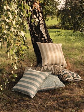 Outdoor cushions piled underneath a tree in summertime