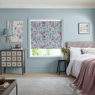Blue roller blind with pink floral print in bedroom