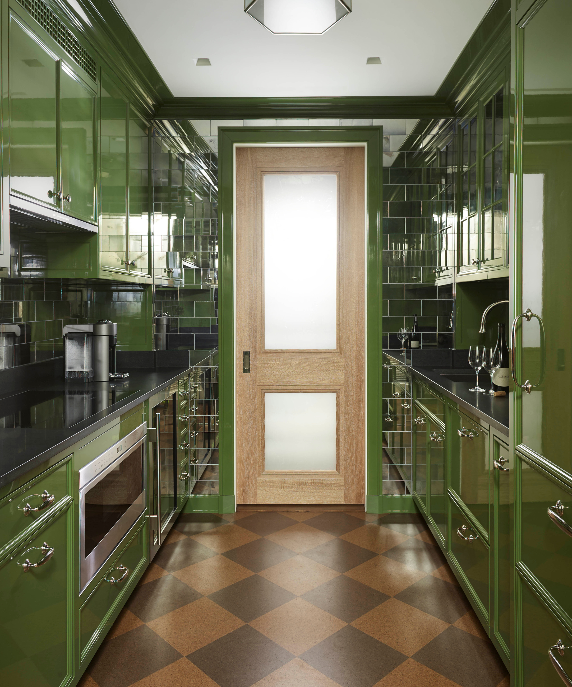 a galley kitchen with high gloss green painted cabinetry