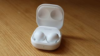 Samsung Galaxy Buds 2 Pro ligger i sitt laddningsfodral på ett träfärgat bord.