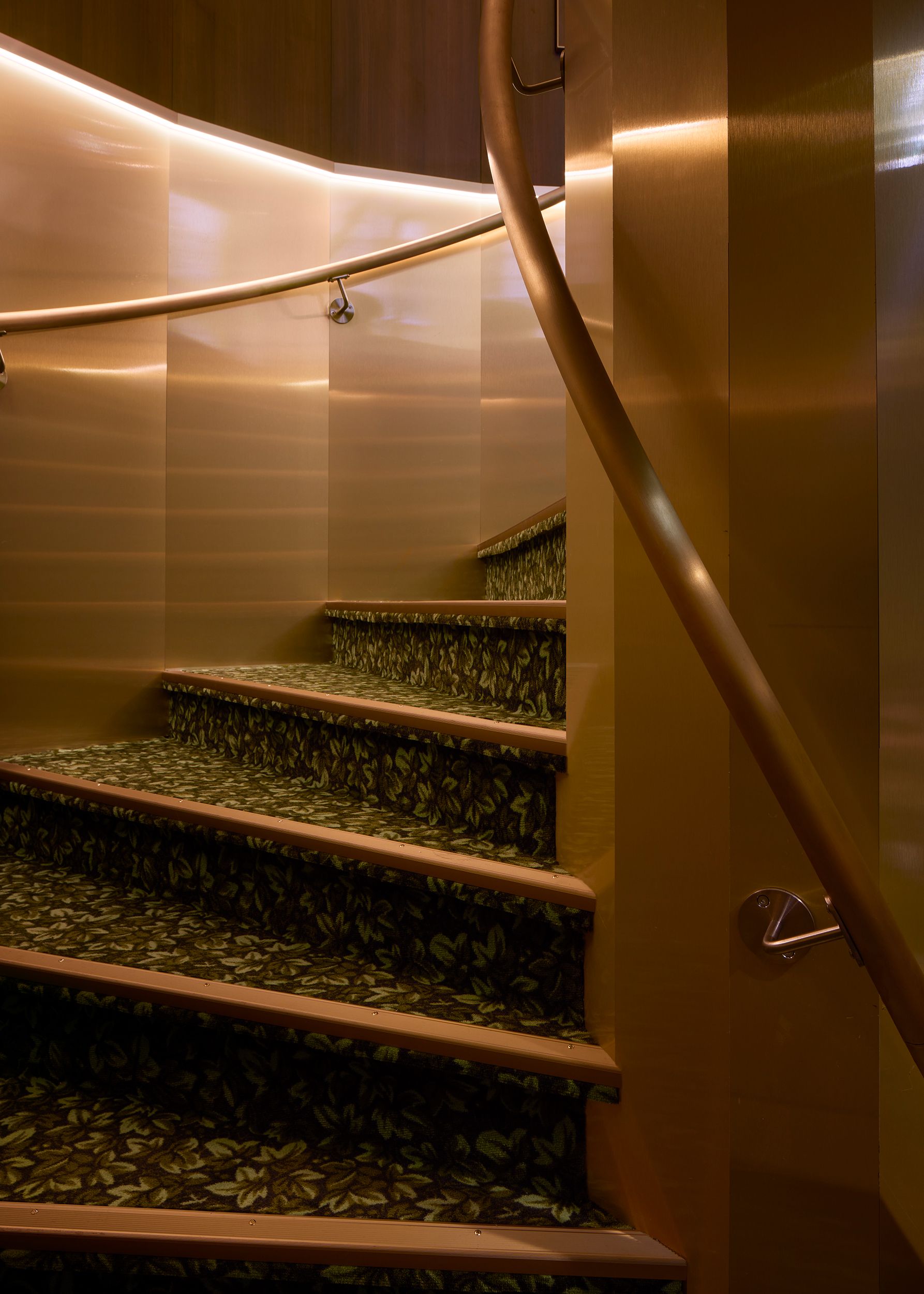 A series of interior shots depicting the retro-futuristic decor of a cinema captures velvet-clad rooms with a palette of reds, pinks, and pale dark greens, theatrical doorways, either arched or draped in curtains, ceiling porthole windows, and a vintage, golden entrance with red neon lights.