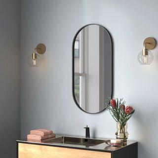 A Destefano Oval Pill-Shaped Metal Mirror in a bathroom