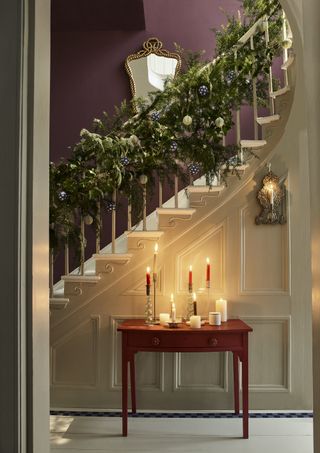 Hallway with a whimsical fresh stairway garland and a styled console table with candles