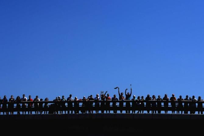 A silhouette of the fans watching from a bridge