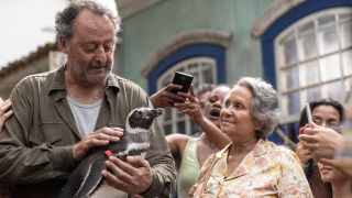 Jean Reno and Adriana Barraza marvel at DimDim in the middle of an eager crowd in My Penguin Friend.