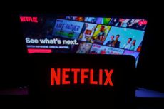 Netflix logo is displayed on a mobile phone screen with Netflix website in a background for illustration