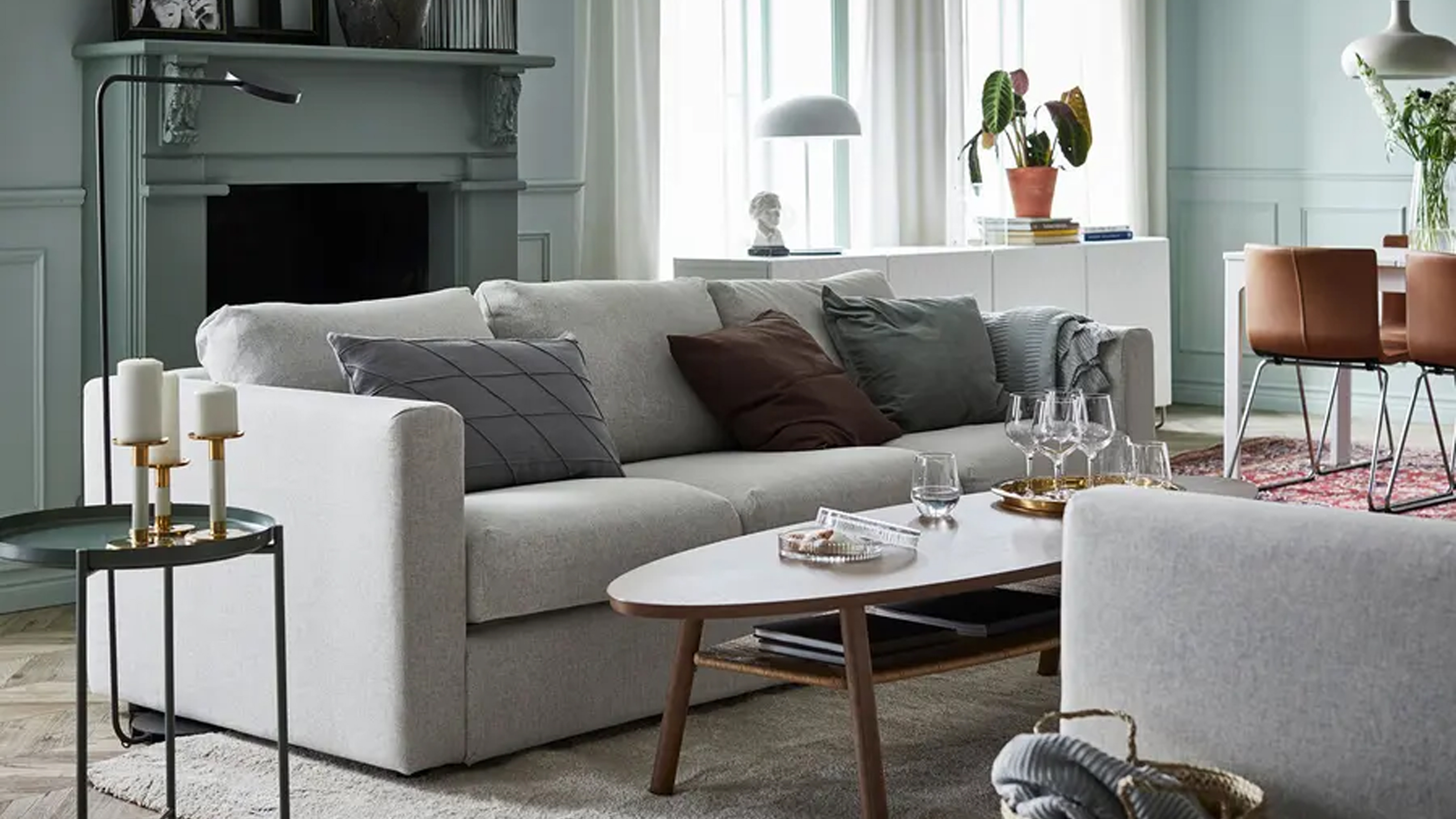A green living room with a grey IKEA sofa in front of a fireplace
