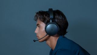 A man wearing the Maxwell 2 gaming headset from Audeze with the microphone extended, with the main looking to the left and the image showing the side of his face.