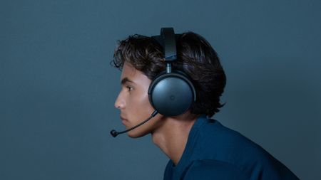 A man wearing the Maxwell 2 gaming headset from Audeze with the microphone extended, with the main looking to the left and the image showing the side of his face.