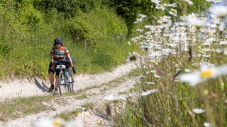 Gravel rider pushing her bike up hill at Dorset Dash event