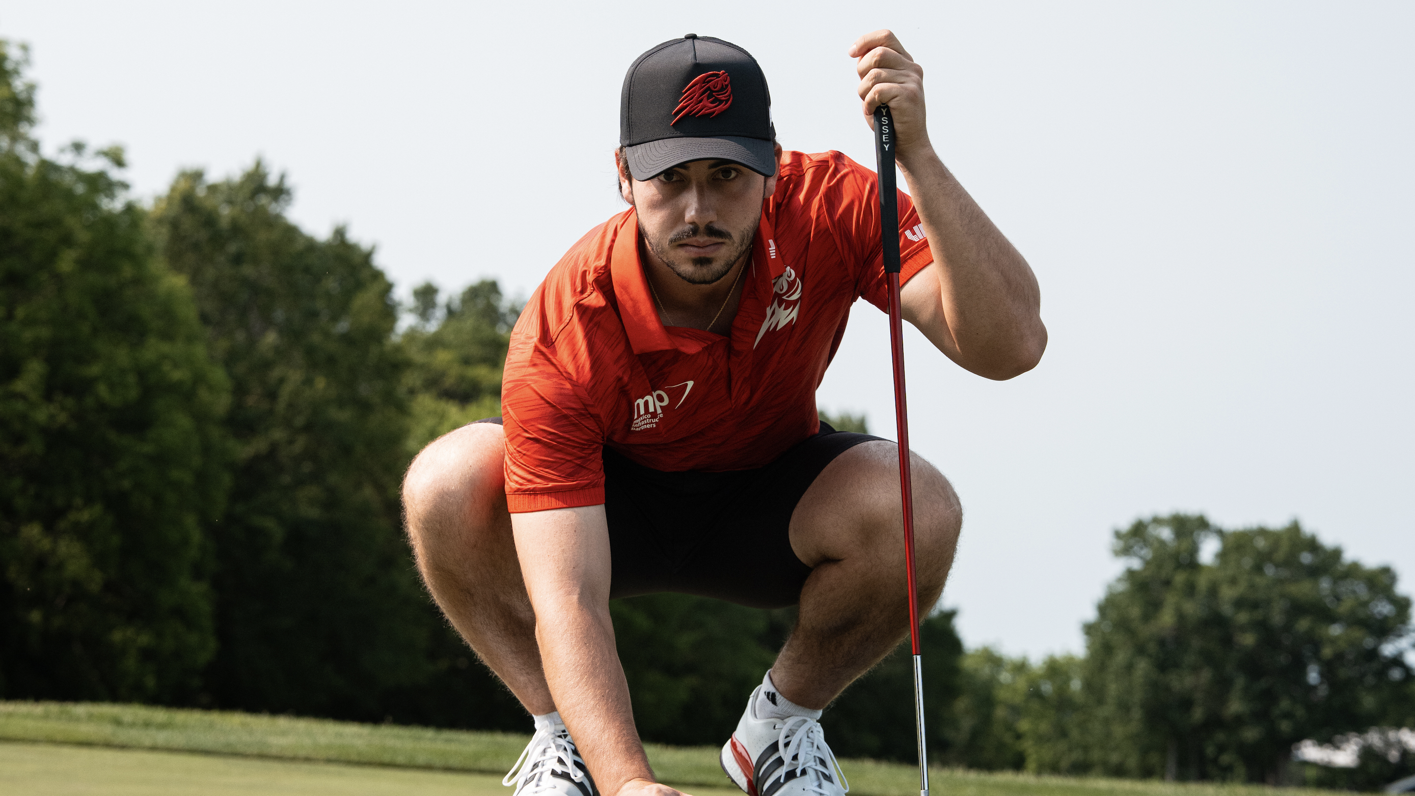 Josele Ballester crouches down to line up a putt in Fireballs GC apparel