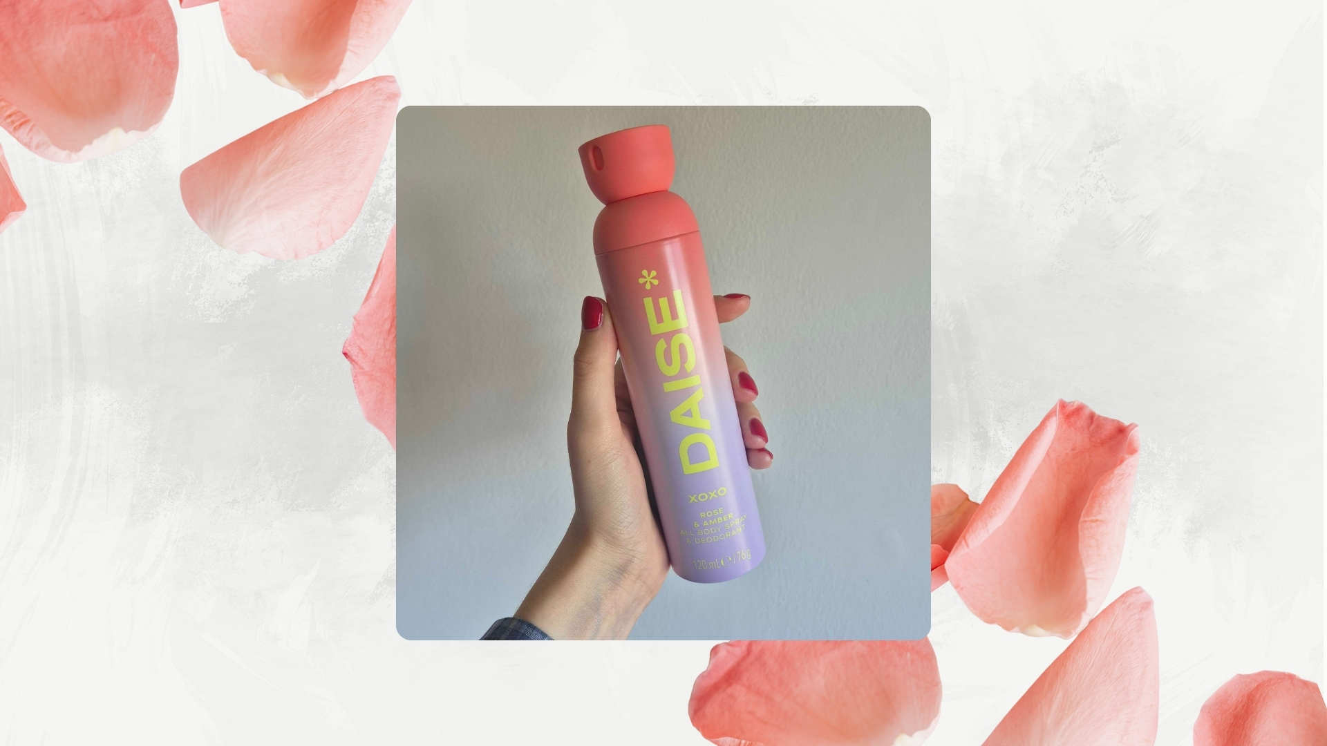 A picture of Digital Beauty Writer, Naomi Jamieson holding a coral and purple bottle of the DAISE All Body Spray &amp; Deodorant Xoxo/ in a white and grey background with pink rose petals.