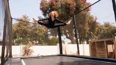 Woman bouncing on trampoline, performing the splits in midair