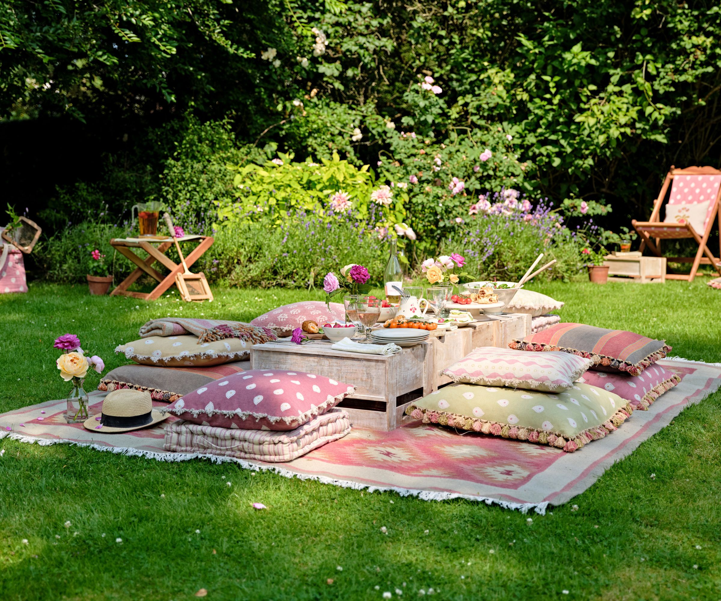 Garden picnic with a colorful rug, floor cushions and low tables