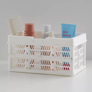 A white shower caddy is like a crate, with products inside of it