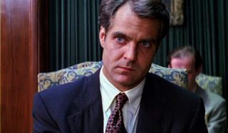 Henry Czerny sitting in a restaurant, looking concerned, in Mission: Impossible.